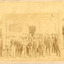 Group of workmen in hats standing in front of a building, the sign of which reads "The Owens & Murray Advertiser." 
