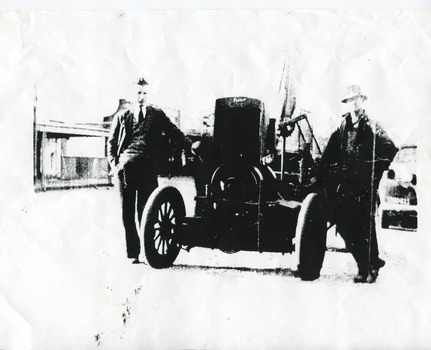 Two men facing the camera standing with a sawbench between them