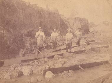 Four miners standing in mining sluice  at Three Mile Goldfields