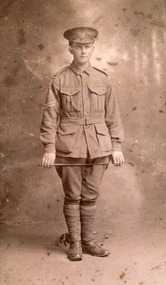 Sepia photograph of William Edward Peach,  a WWI soldier in uniform holding a crop across his thighs.