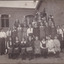 Photograph depicting a group of school girls and teachers posing outside a brick school building