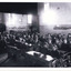 Black and white photo of a crowded early 20th-century classroom with children seated at wooden desks.