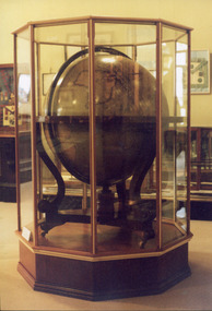 Large wooden globe of the world encased in a glass and wood display case.