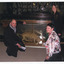 A crouching man and women surround a glass case containing a Thylacine, another women is standing next to the case. They are all smiling at the camera and behind them are hundreds of taxidermy specimens lining the wall, also in glass cases.