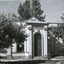 Two medium sized trees stand either side of the entrance to a classical style building, above the doorway is inscribed 'library' and the year '1856'.