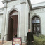 Woman wearing warm clothes is standing in front of the Burke Museum entrance. On her left side there is a sign saying "Burke Museum" with a hand pointing to the right.