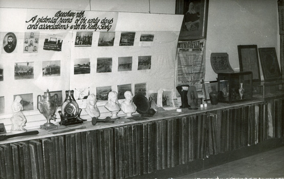 Black and white photograph of museum collection featuring busts, a photo display and other objects