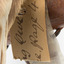 Barking Owl standing on a wooden platform with swing tags attached. Close-up view of torn swing tag  (see transcription).