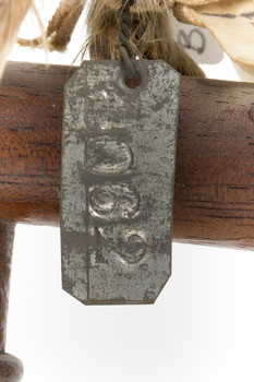 Ural Owl mounted on wooden perch pedestal with swing tag. Close-up view of metal swing tag attached to lower right leg (see transcription).