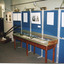 Colour photograph of "The Harvest" exhibition with a display cabinet with objects inside surrounded by blue boards displaying photographs and information. Just next to the cabinet is a seed distributor, behind which is a grain mill.