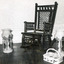 Black and white photograph of a rocking chair, a kerosene lamp, a bottle holder, and two epergnes.