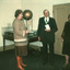 A colour photograph of two women and a man in front of an exhibition display table.
