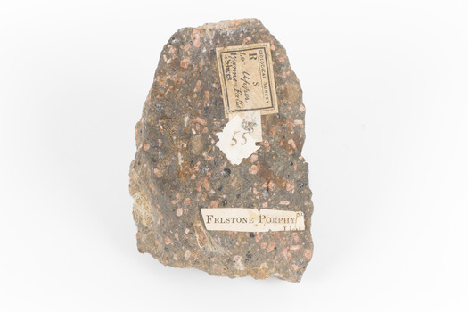 A solid, dark grey mineral specimen with pale terracotta coloured inclusions