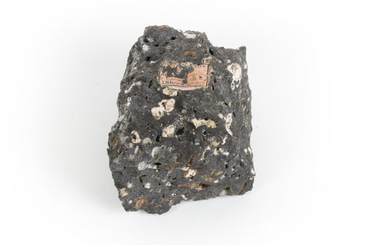 A smaller than hand sized rock specimen which is dark grey in colour with small holes and white deposits across its surface.