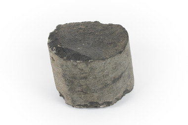 A small cylinder shaped piece of Basalt with smooth sides and broken top and bottom edges. 