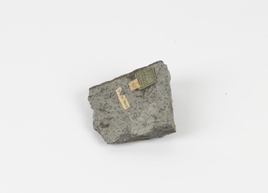 A disfigured rectangular like shape of fine-grained, poorly foliated, porphyroblastic metamorphic rock. The spotted slate is light grey in colour with darker flecks throughout. 