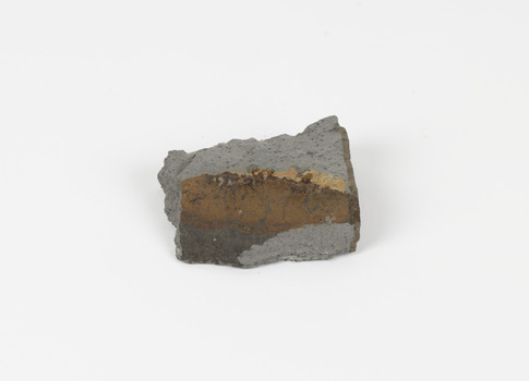 A disfigured rectangular like shape of fine-grained, poorly foliated, porphyroblastic metamorphic rock. The spotted slate is light grey in colour with darker flecks throughout.