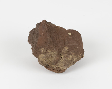 A cut rock with some natural curves of a brown hue. The rock is very porous and shows layers. An existing label depicts the number 42.