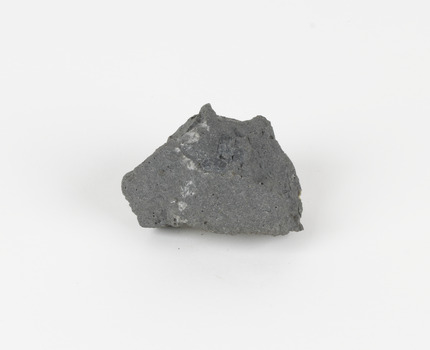 An angular, hand sized grey geological specimen in white spotted grey colours.