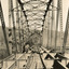 A bridge under construction in sepia. The perspective is from inside the bridge, looking along to one end, with iron trusses on either side, iron struts and bracing above, and floor beams below strewn with wooden planks.