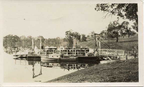 Type of boat, called a punt, docked at pier on a riverbank