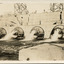 Open valves of a dam showing water flowing into stream of water, background shows scaffolding on wall of dam.
