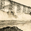 Water rushing down a dam embankment with scaffolding on running along behind the water on the top of the embankment