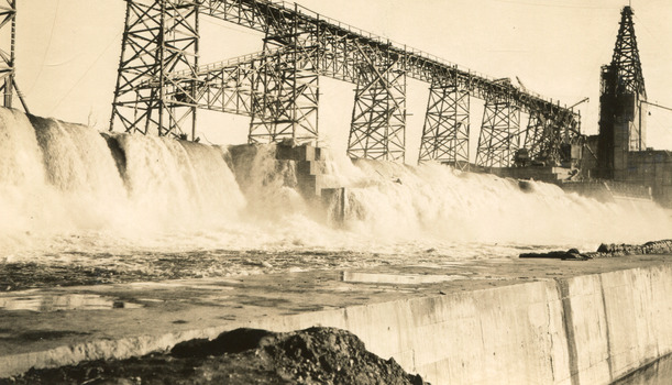 Water rushing down a dam embankment with scaffolding on running along behind the water on the top of the embankment