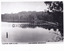 Black and white photograph taken from one side of the lake, long narrow jetty in the middle ground. A person is standing at the start of the jetty which is connected to the sole road on the images proper left. Trees line the bank in the background. Text underneath the image reads "Valentine series No.1862 Lake Kerferd, Beechworth". 