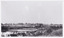 View of Lake Sambell while it was under construction, there is shrubbery in the foreground, and in the back there are rows of trees.
