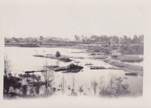 Photograph depicting Lake Sambell with low water revealing small islands and boat in foreground. 