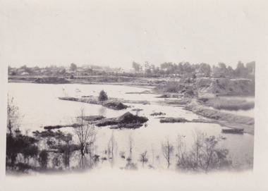 Photograph depicting Lake Sambell with low water revealing small islands and boat in foreground. 