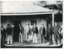 Taken c1900, six elderly Chinese men and two local Beechworth men stand in a row outside a  weatherboard miners hut. The Chinese men wear trousers and jackets with hats or caps, three lean on walking sticks. The two men on the right wear black suits and top hats. The man second from the right is believed to be a Chinese Presbyterian minister.