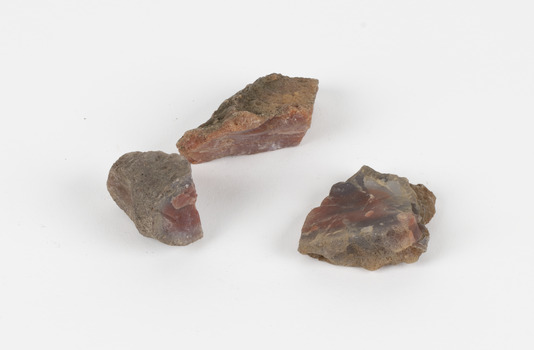 The image shows three pieces of stone with a russet interior hue and a grey/brown porous crust. 