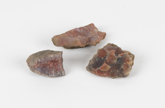 The image shows three pieces of stone with a russet interior hue and a grey/brown porous crust. 