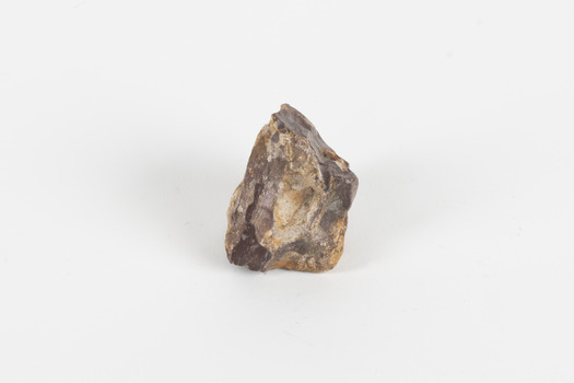 A palm-sized uncut mineraloid specimen in shades of brown, orange, and white.