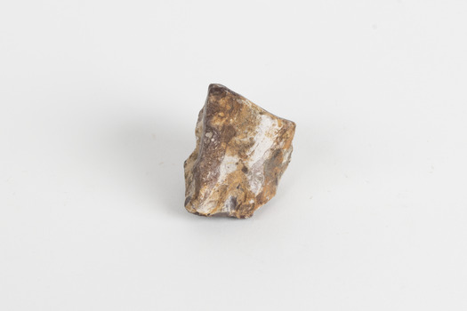A palm-sized uncut mineraloid specimen in shades of brown, orange, and white.