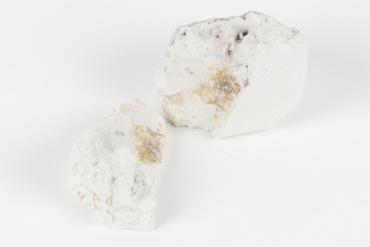 Two hand-sized solid mineral specimen in shades of white and gray 