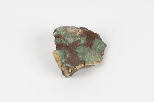 A hand-sized solid mineral specimen in shades of cream, ochre, brown and green