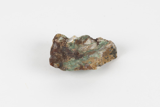A hand-sized solid mineral specimen in shades of cream, ochre, brown and green