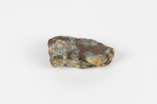A hand-sized solid mineral specimen in shades of cream, ochre, brown and green