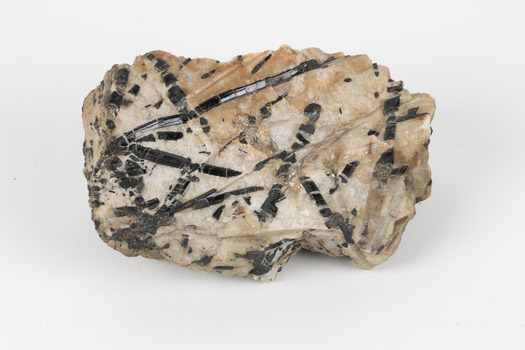 A medium-sized cream and ochre coloured solid mineral specimen with multi-directional black criss-crossing lines. 
