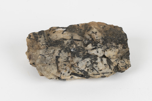 A medium-sized cream and ochre coloured solid mineral specimen with black mineral speckling in places. 