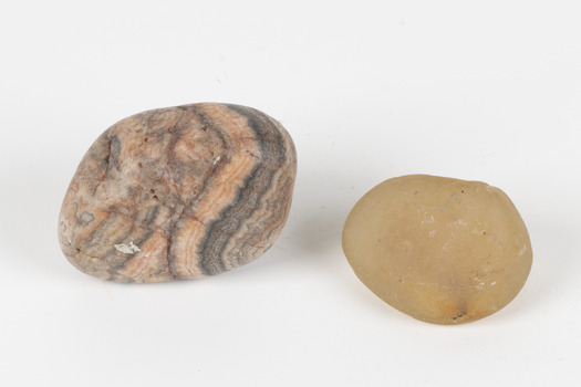 The photograph shows one larger piece of Agate in shades of peach and grey and a smaller piece of orange quartz. 
