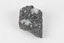 A flat hand-sized grey mineral specimen with translucent white crystallised formation on top. 