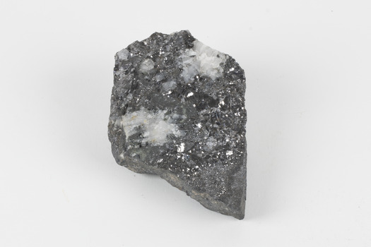 A flat hand-sized grey mineral specimen with translucent white crystallised formation on top. 
