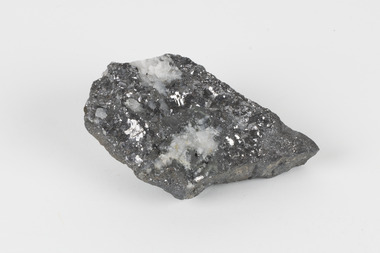 A flat hand-sized grey mineral specimen with translucent white crystallised formation on top. 