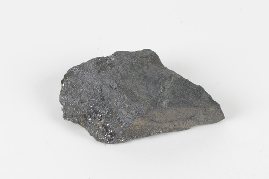 A flat hand-sized grey mineral specimen with translucent white crystallised formation on top. 
