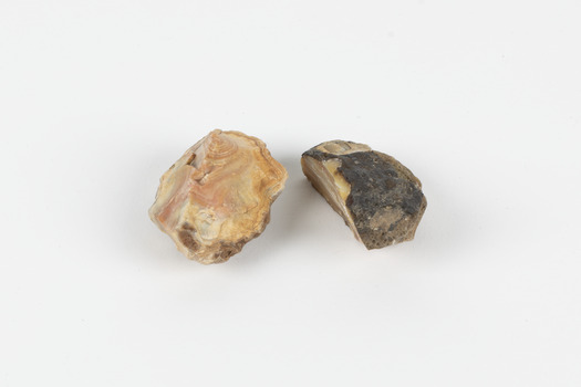 Two egg-sized solid mineral specimens displaying light and dark brown matrix and peach/orange toned agate. 