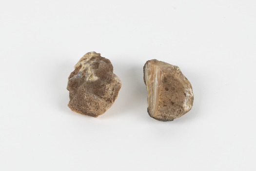 Two egg-sized solid mineral specimens displaying light and dark brown matrix and peach/orange toned agate. 